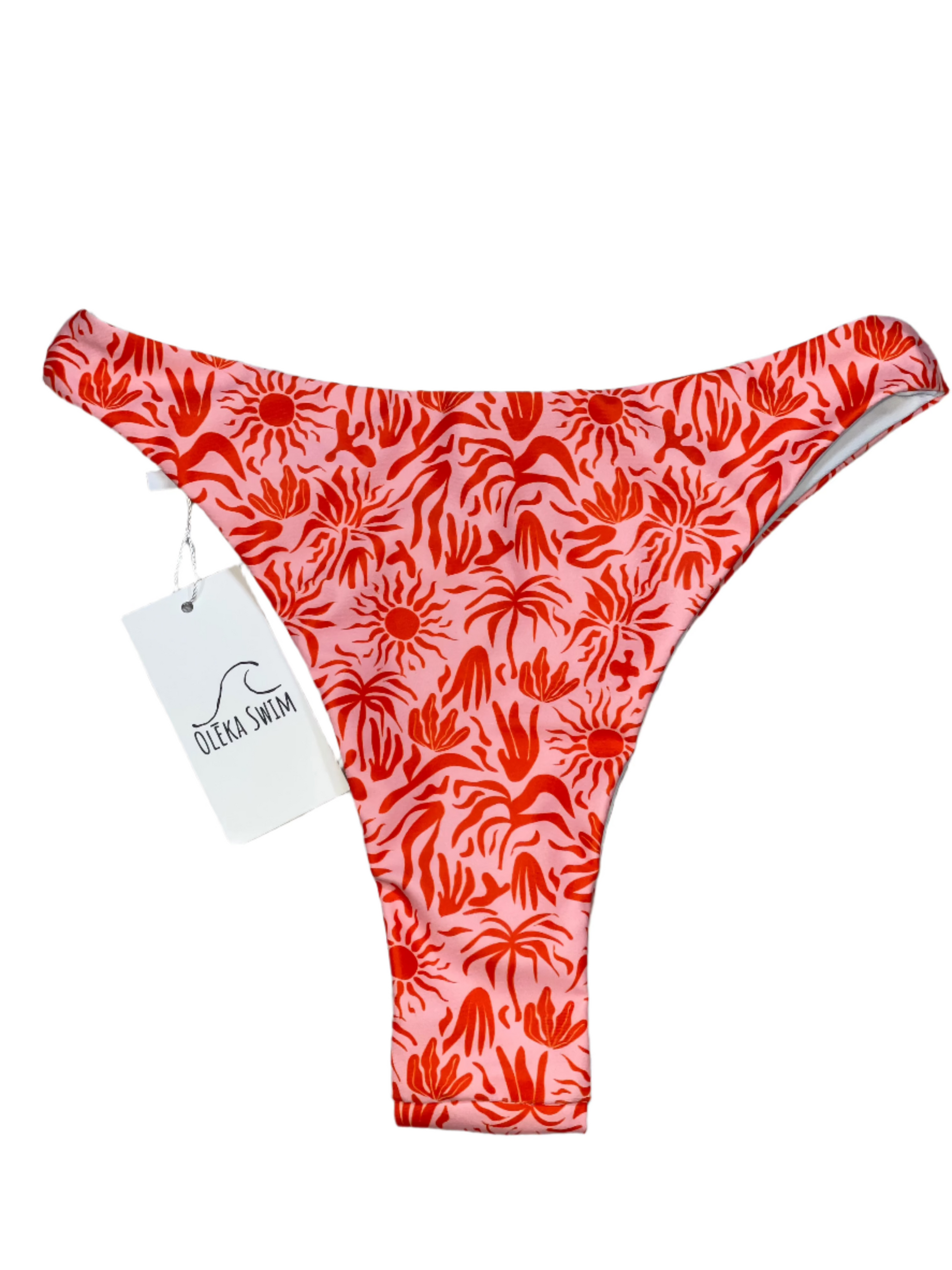 The Lola bikini bottom in a vibrant red and pink tropical pattern, featuring sun motifs and palm leaves. The bikini bottom is displayed flat on a white background with a tag attached, labeled 'Oleka Swim.