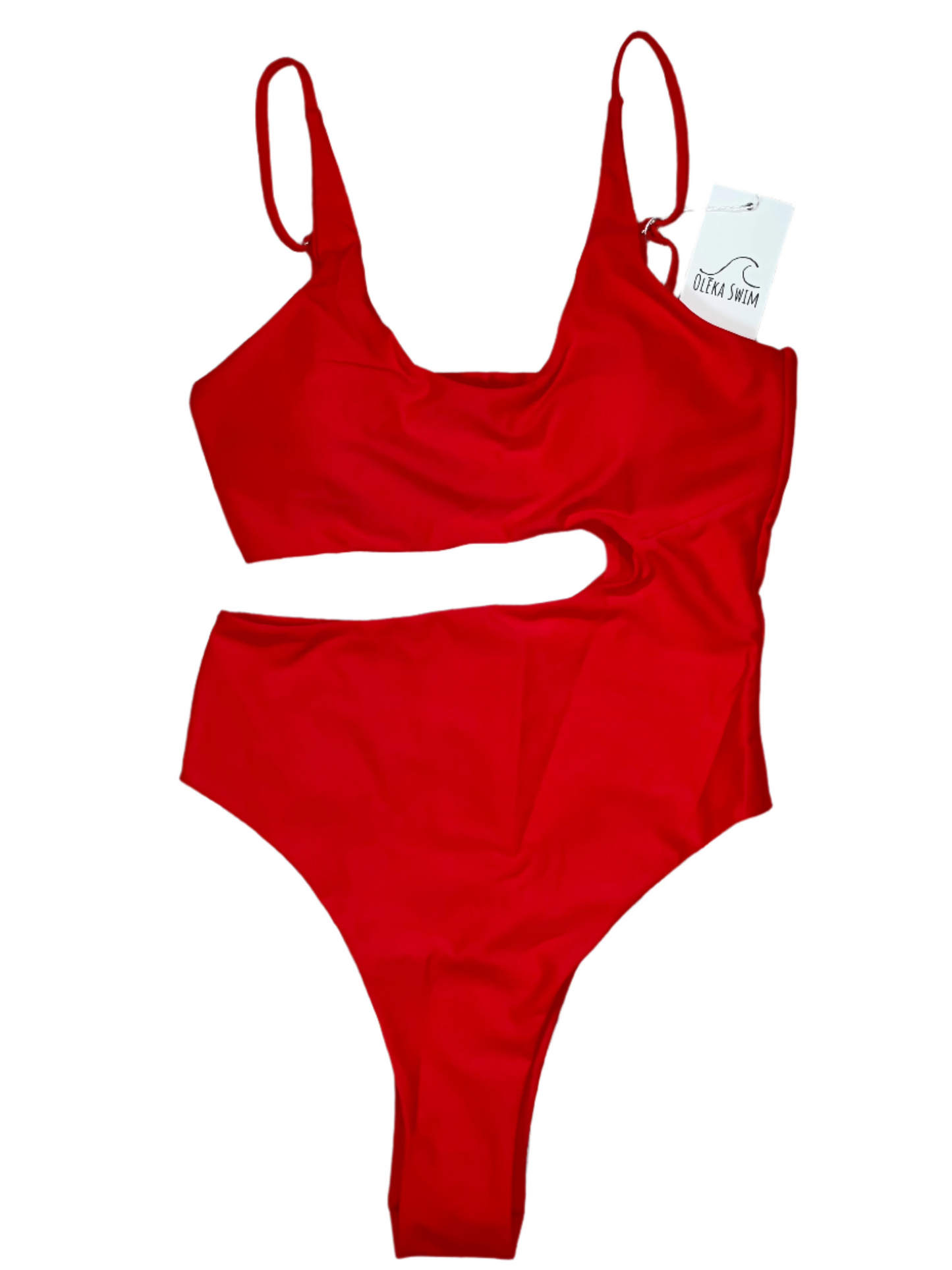 The Nala One Piece swimsuit from Oleka Swim, displayed flat on a white background. The swimsuit is a vibrant red color, featuring a stylish cutout on the side and adjustable shoulder straps. A tag reading 'Oleka Swim' is attached to the swimsuit.